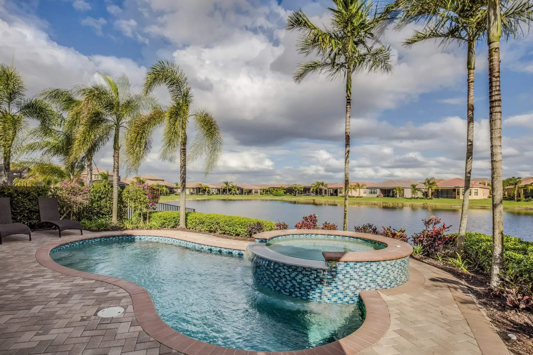 Freeform pool with a raised mosaic-tile spa overlooking a lake