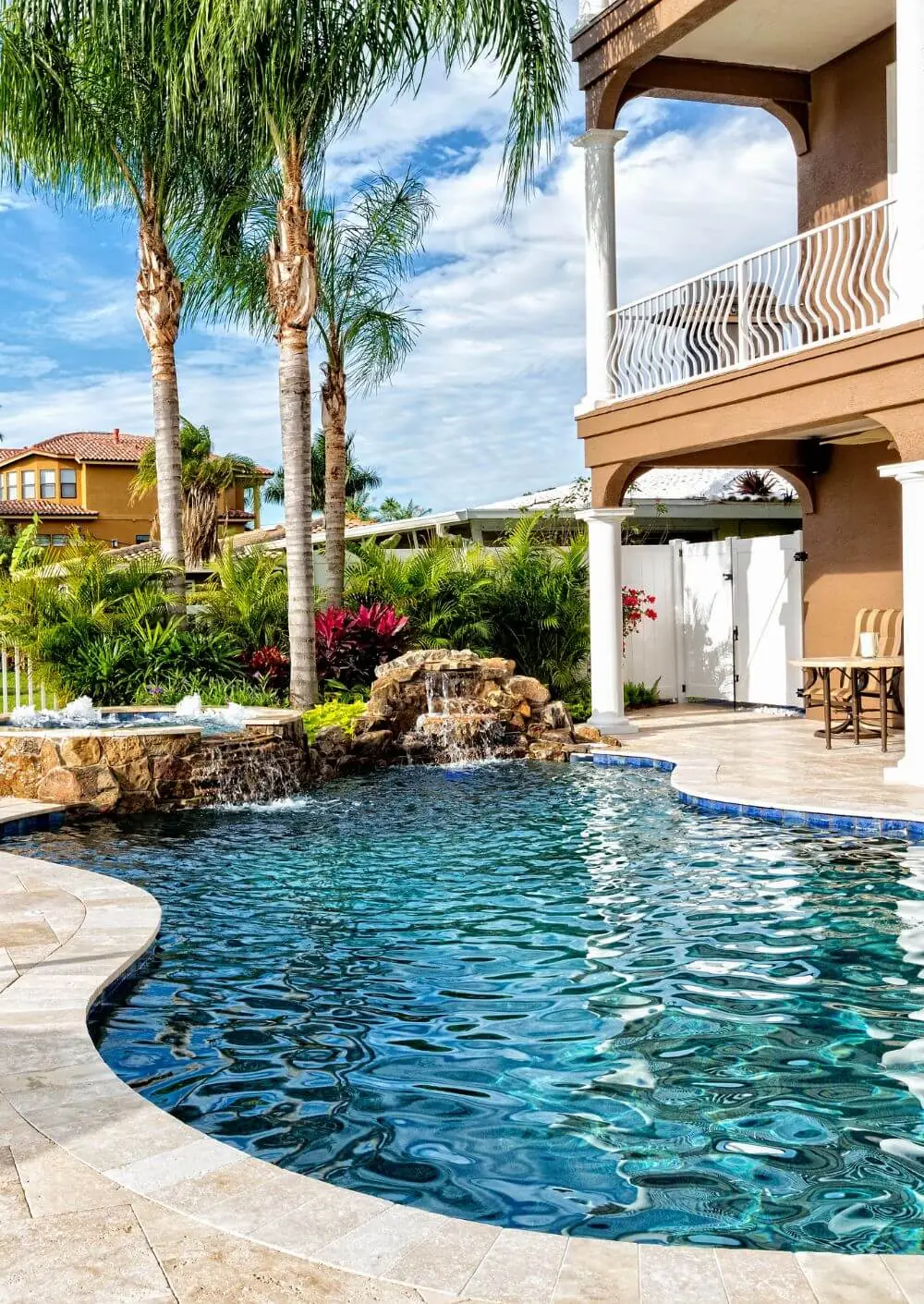 Freeform pool with a rock waterfall below a home's balcony