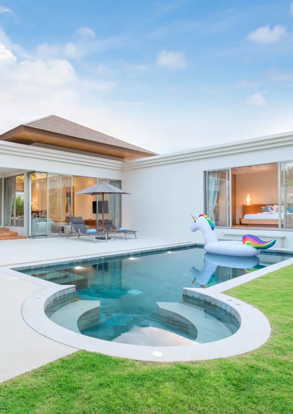 Pool with a round spa and a unicorn float beside a modern white home
