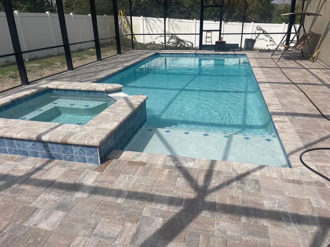 Screened rectangular pool with a raised spa and paver deck