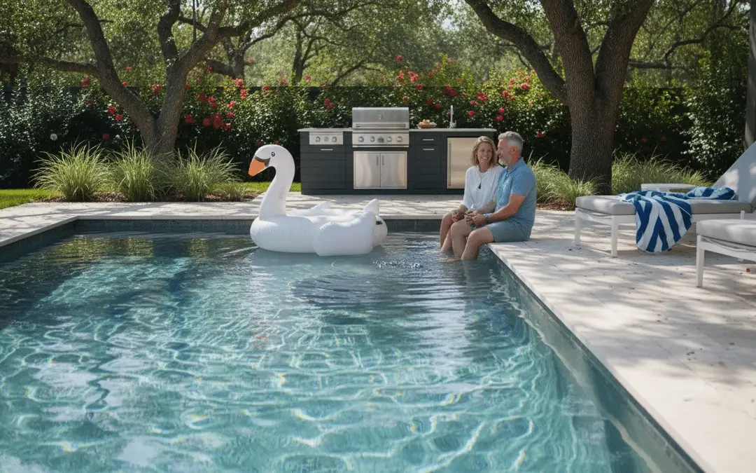 Couple sitting on the edge of a rectangular pool with a swan float and outdoor kitchen