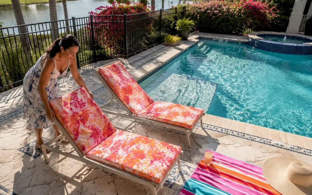 Woman preparing poolside loungers in backyard