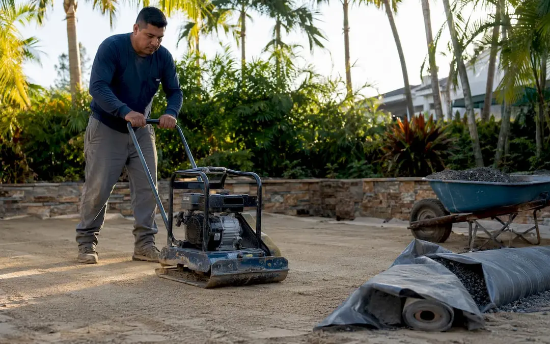 Worker compacting soil base for pool pad